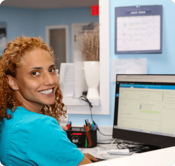 Smiling woman working at a computer desk.